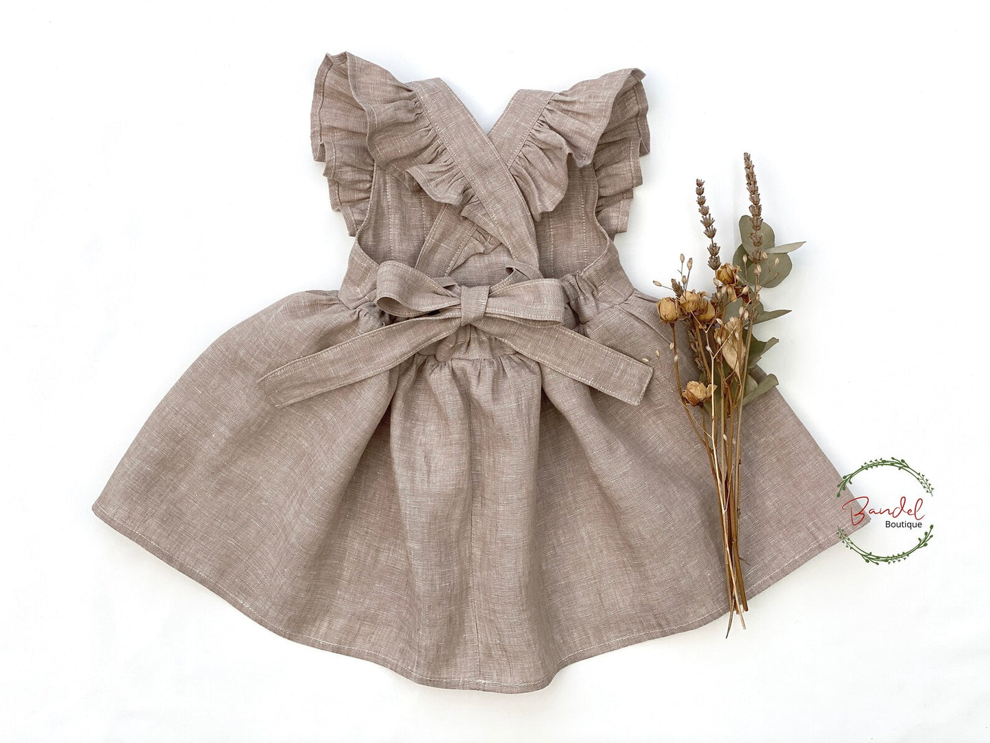 Brown dress with ruffled straps and a bow on a white background