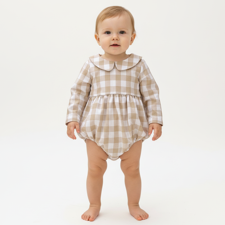 Baby wearing a checkered romper on a white background
