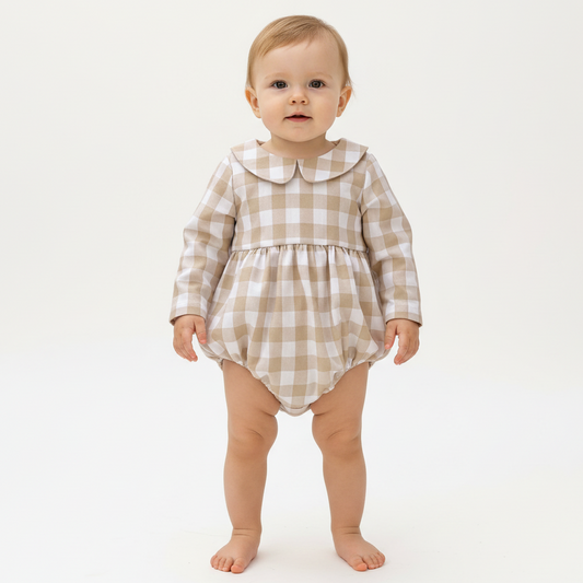 Baby wearing a checkered romper on a white background