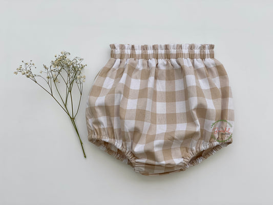 Beige Gingham Bloomers features frills at the waist and an elastic waistband and leg openings, all made with sustainable and comfortable materials, perfect for your baby. Their breathability and durability make them an ideal addition to your little one's wardrobe.
