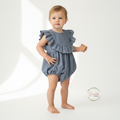 Baby wearing a blue ruffled romper on a white background