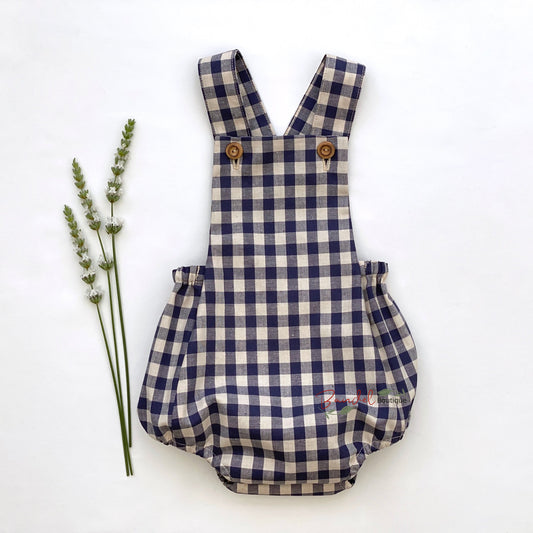 Adorable blue gingham baby romper featuring adjustable straps and rustic wooden buttons. 