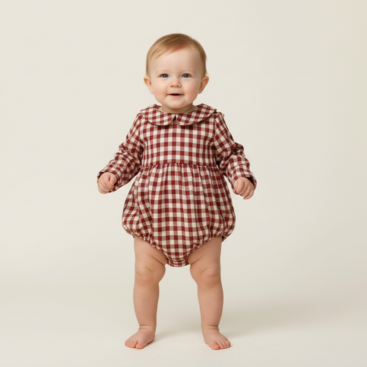 Baby wearing a red and white checkered onesie on a beige background