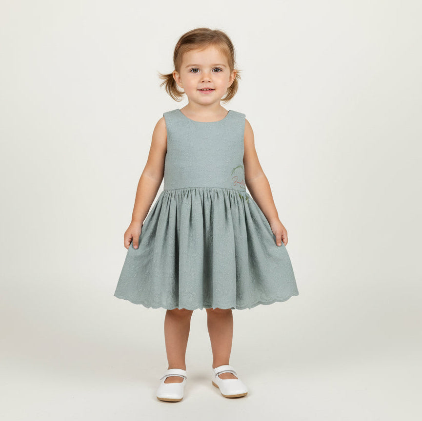 Young girl wearing a dusty mint dress on a white background