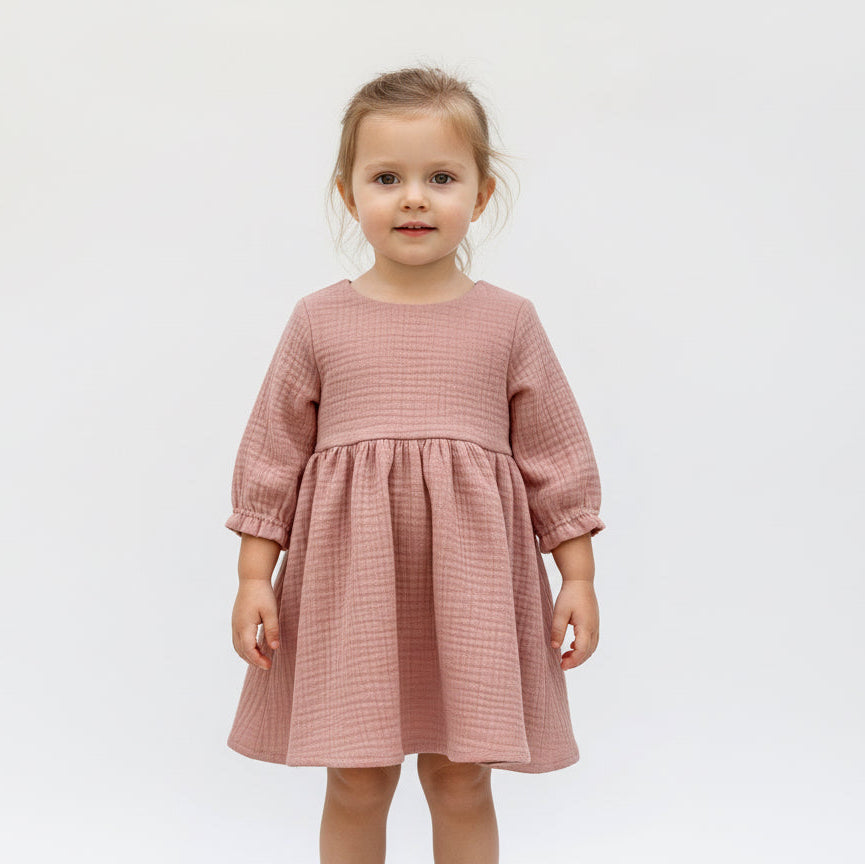 Young girl wearing a pink dress against a white background