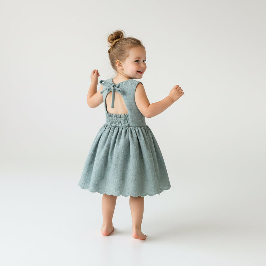 Young girl wearing a dusty green dress on a white background