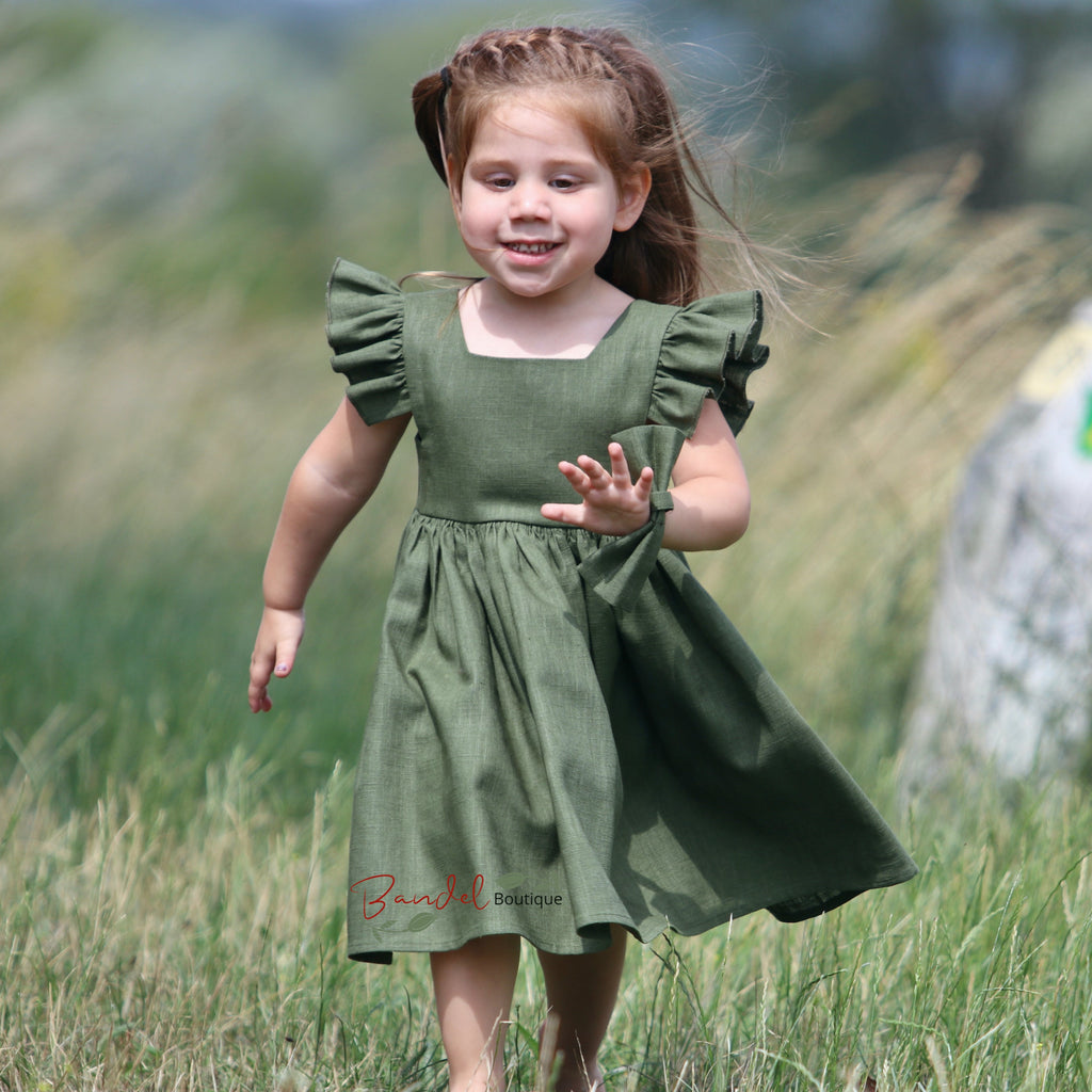 Young girl in a green dress running through a grassy field