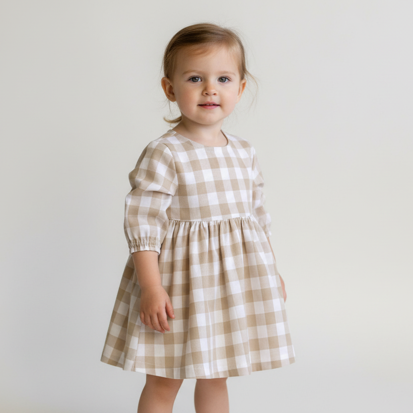 Young child wearing a checkered dress against a plain background