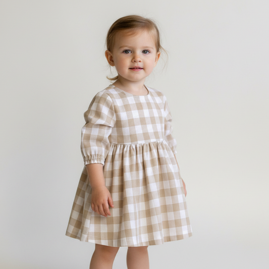 Young child wearing a checkered dress against a plain background
