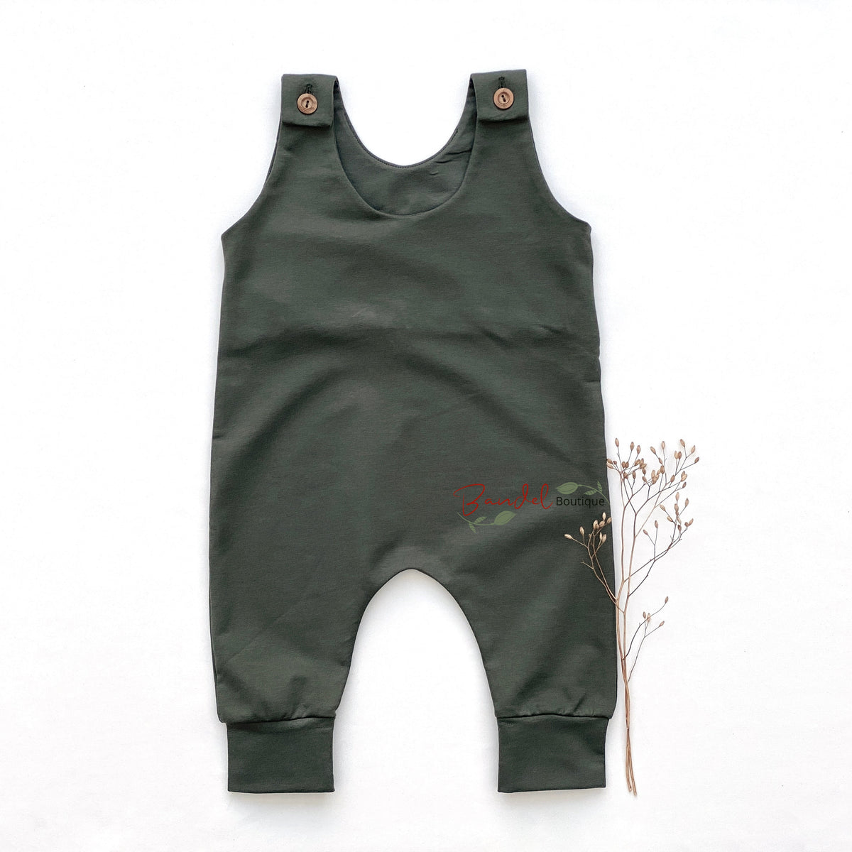 A pair of kids' lounge pants in sage green with a festive Christmas pattern of dogs, Santa Claus, Christmas trees, and skis, featuring a black elastic waistband with white text.