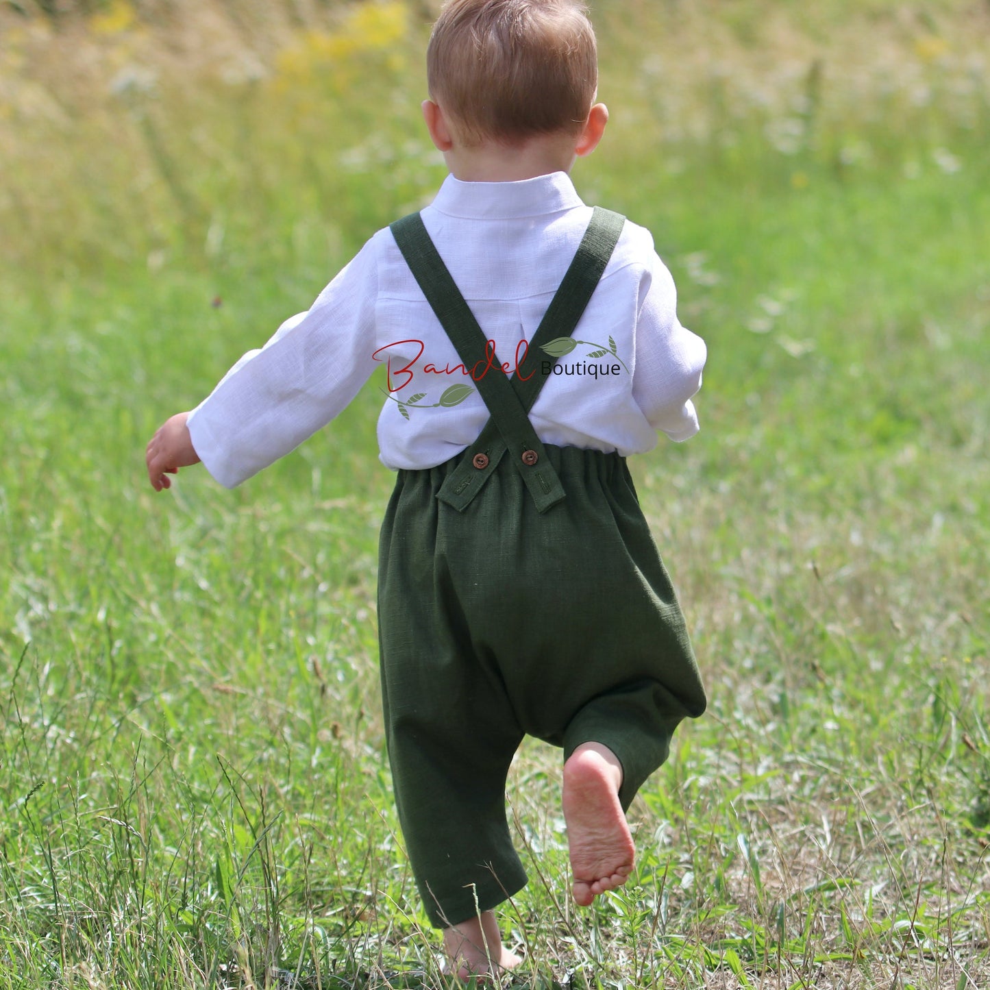 Child wearing a white shirt with suspenders walking in a grassy field