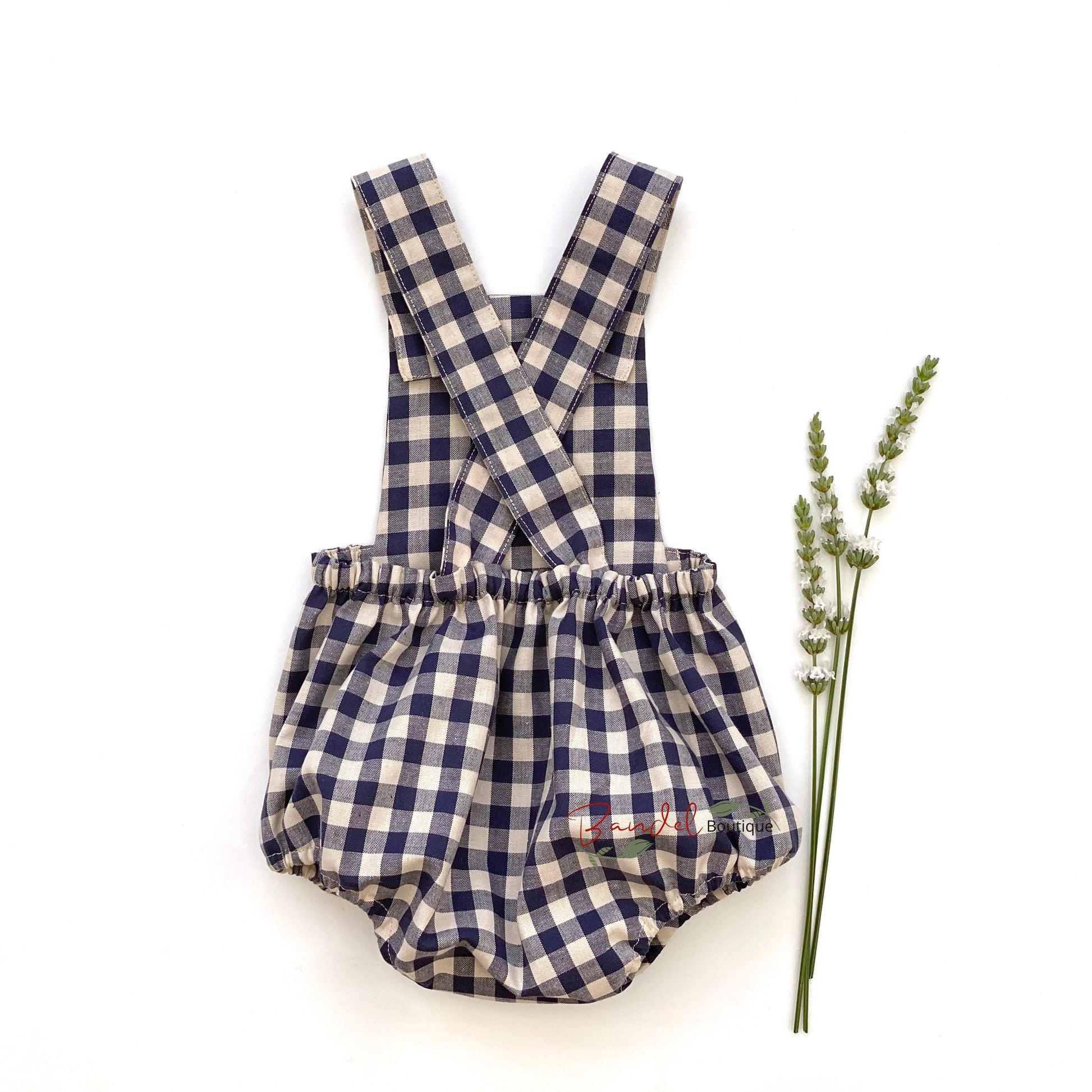 Adorable blue gingham baby romper featuring adjustable straps and rustic wooden buttons.