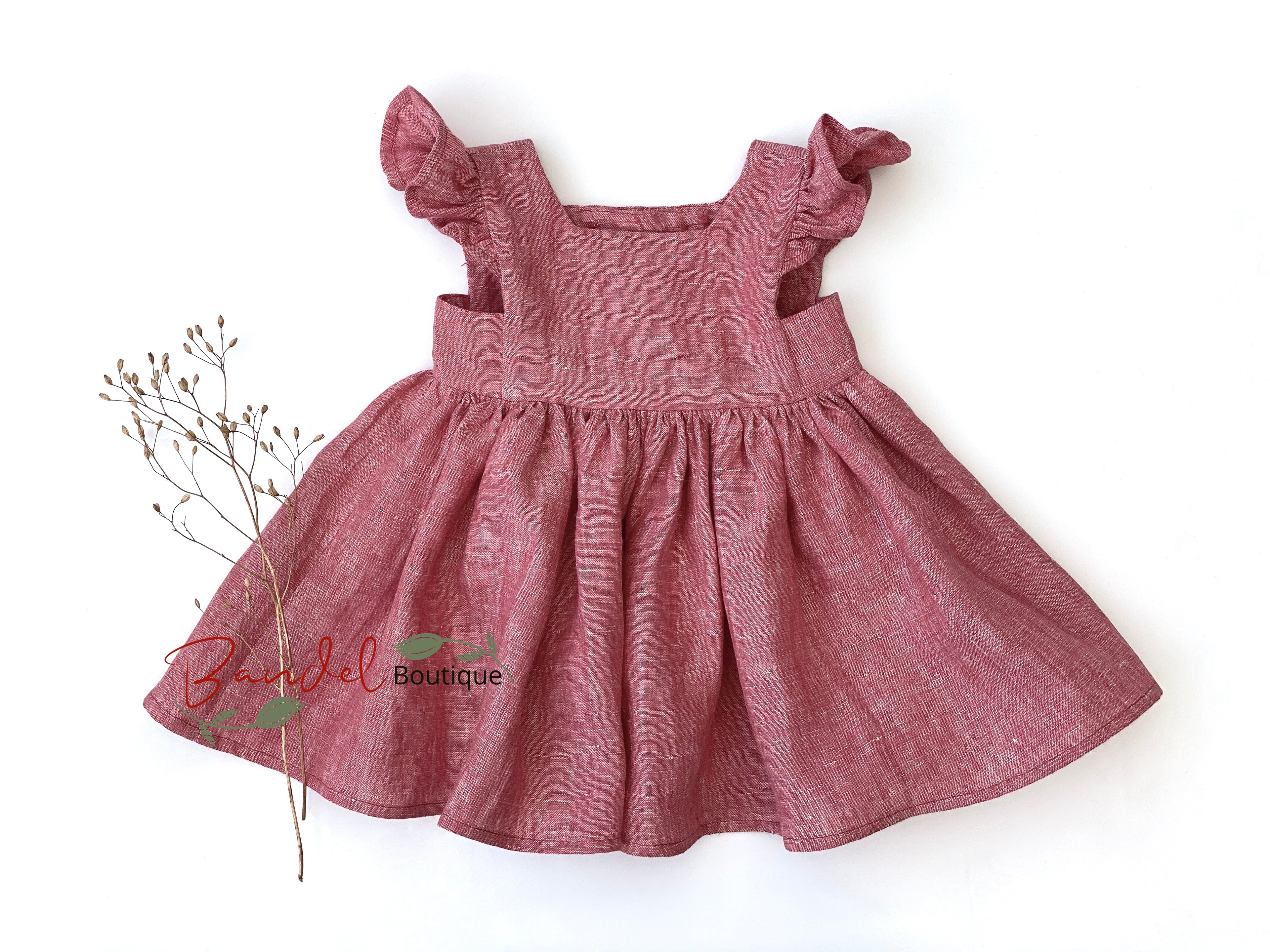 Red dress with ruffled straps on a white background, featuring 'Bella Del' logo.