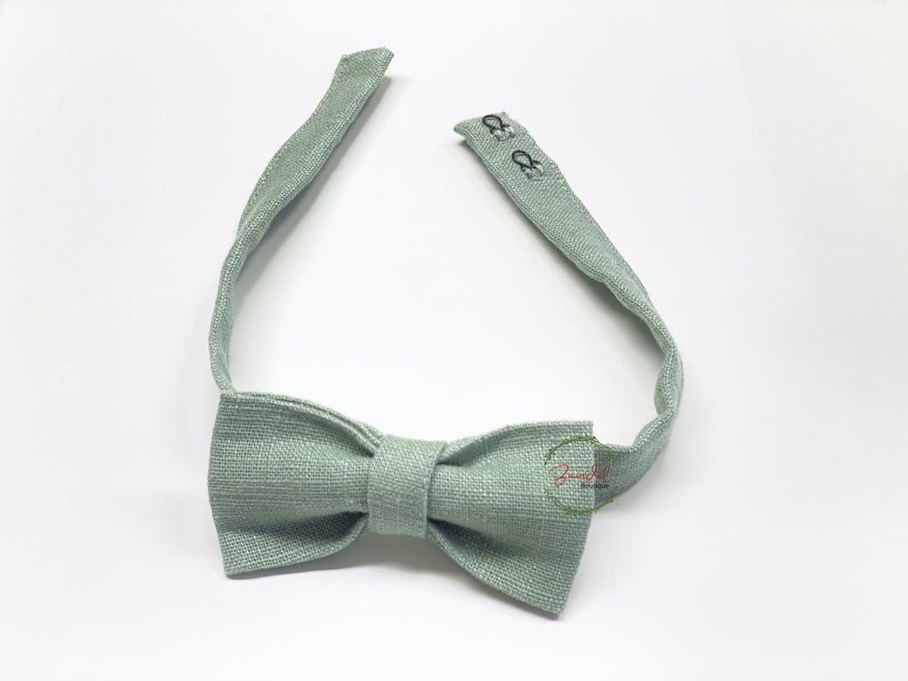 A green classic bow tie made from linen, displayed on a white background.