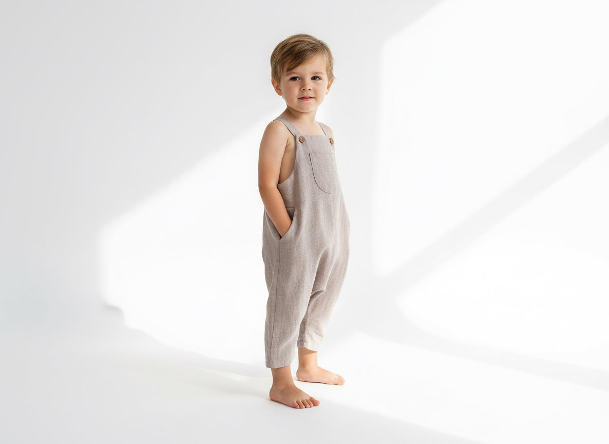 Child wearing a sand overalls standing on a white background