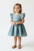 Young girl wearing a light blue dress with ruffled sleeves on a white background