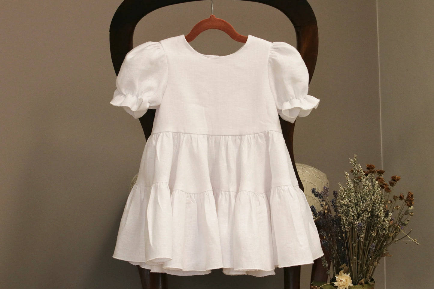 White dress on a wooden chair against a plain background