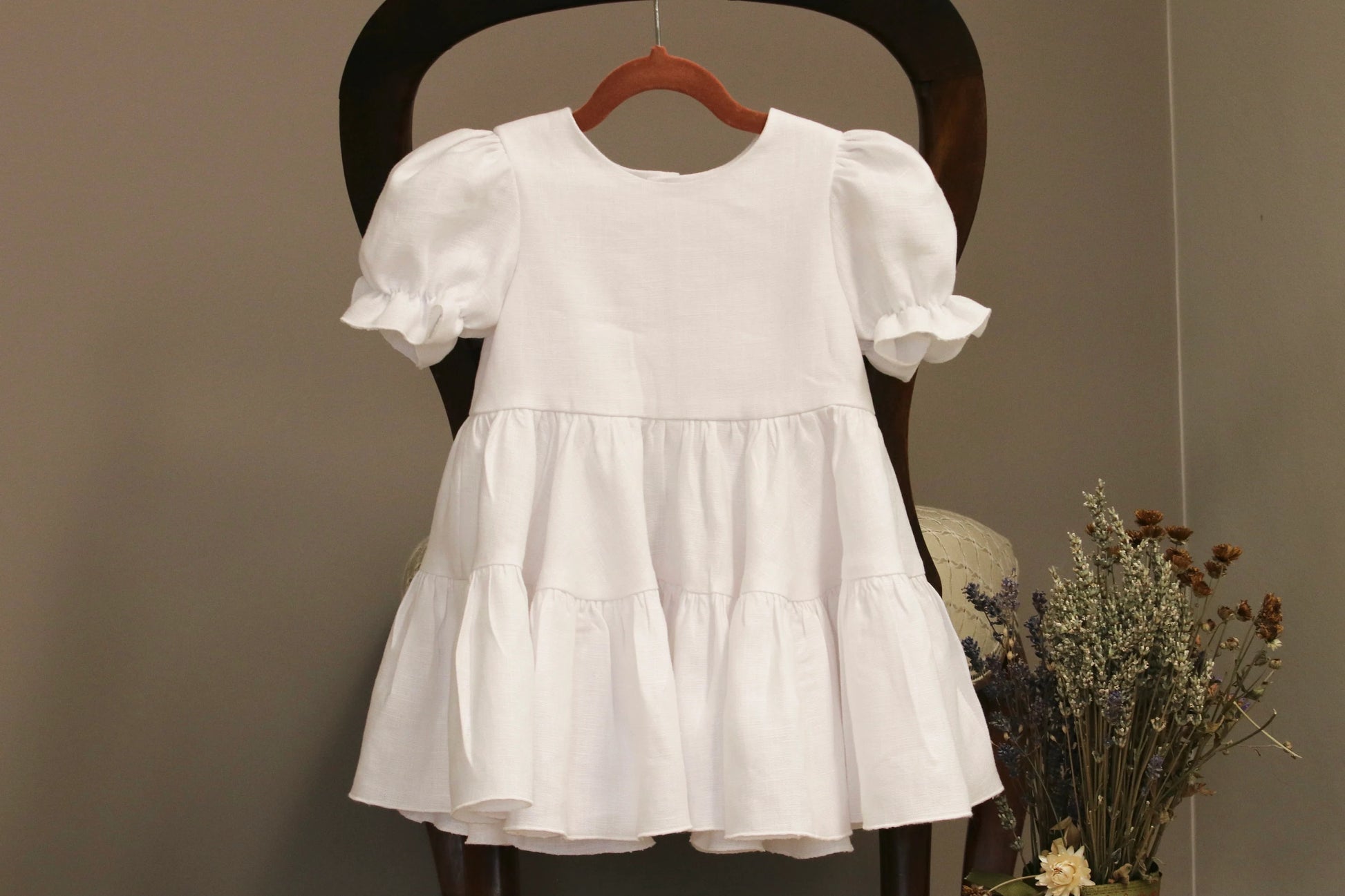 White dress on a wooden chair against a plain background