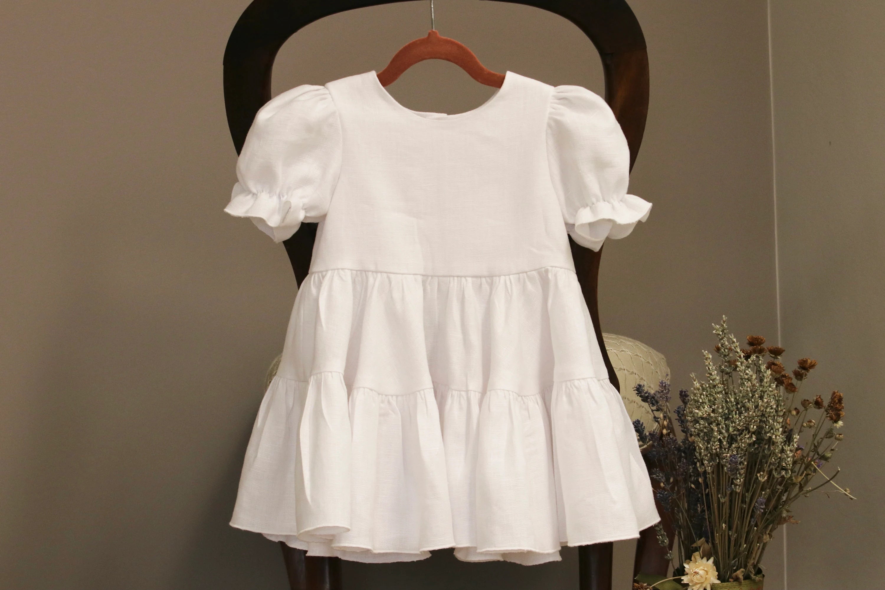 White dress on a wooden chair against a plain background