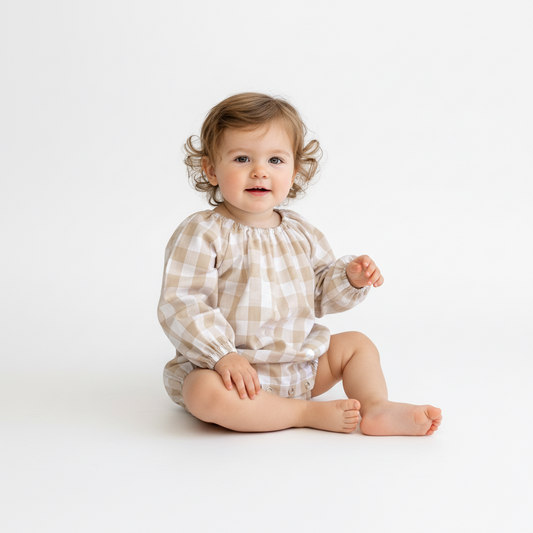 Baby wearing a checkered outfit sitting on a white background