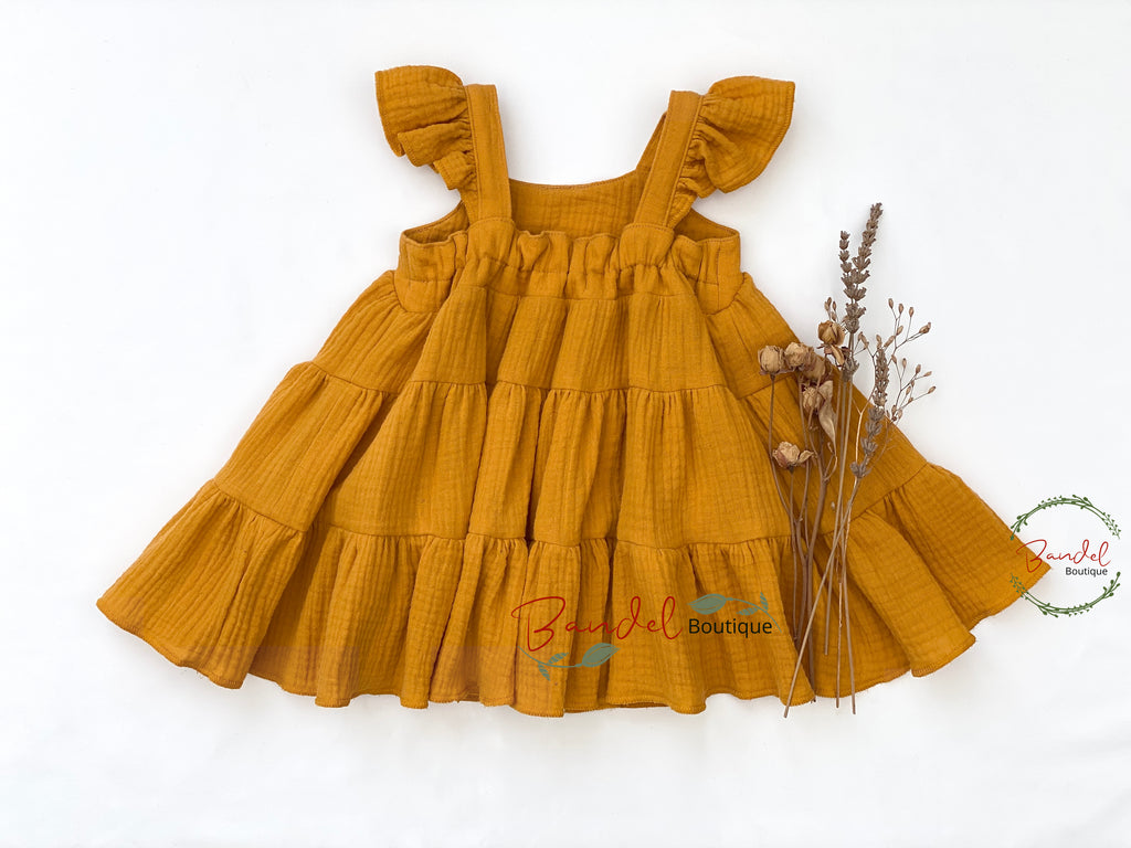 Mustard yellow dress with ruffled sleeves and layers on a white background, featuring 'Bambelel Boutique' branding.