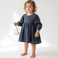 Young child wearing a dark blue dress holding a toy on a white background