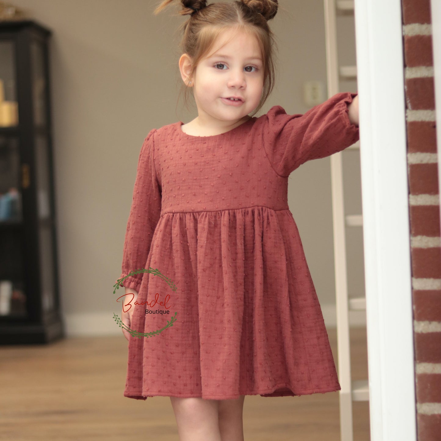 Young girl wearing a red dress standing indoors.
