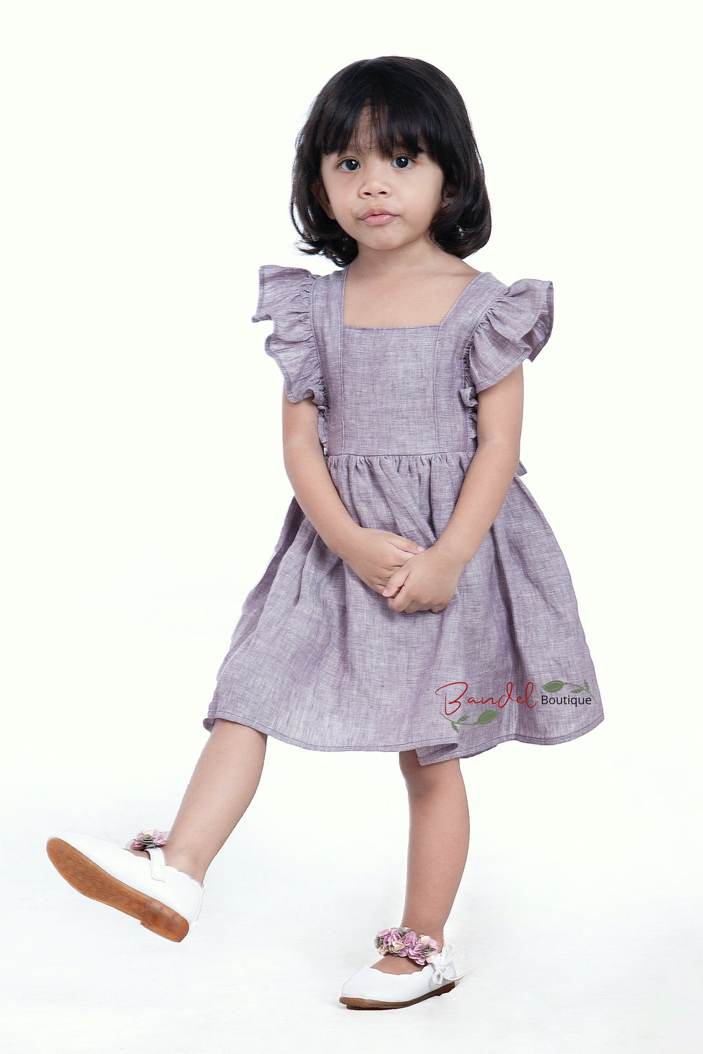Young girl wearing a purple dress with ruffled sleeves on a white background