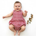 Baby wearing a red and white checkered romper on a white background