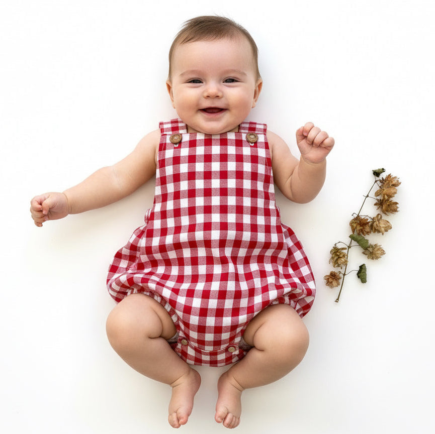 Baby wearing a red and white checkered romper on a white background