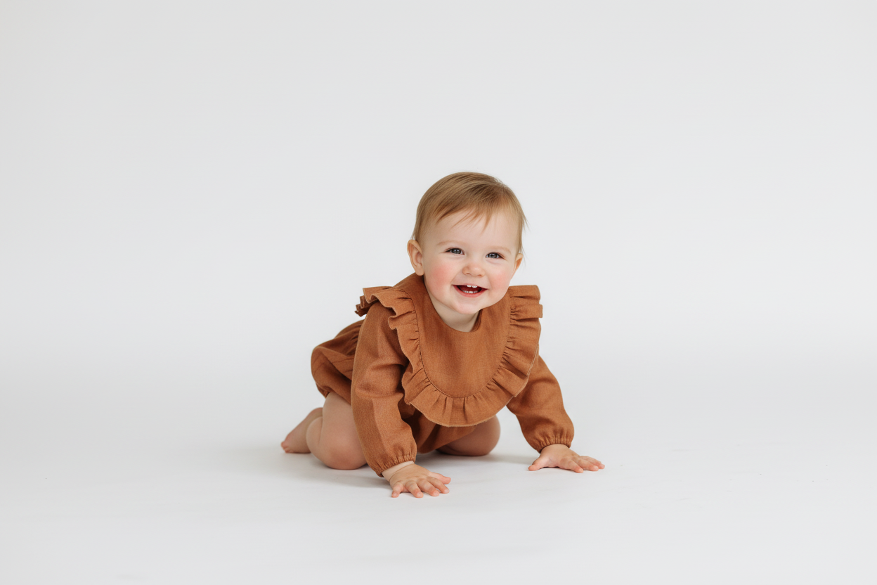 Baby wearing a brown ruffled romper on a white background