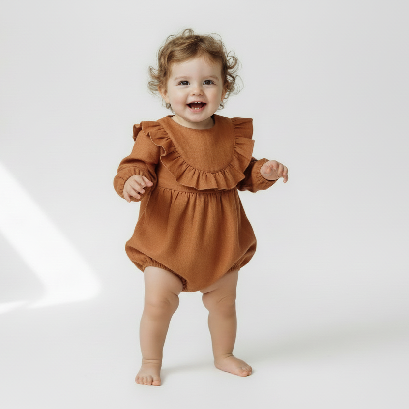 Child wearing a brown ruffled romper on a white background
