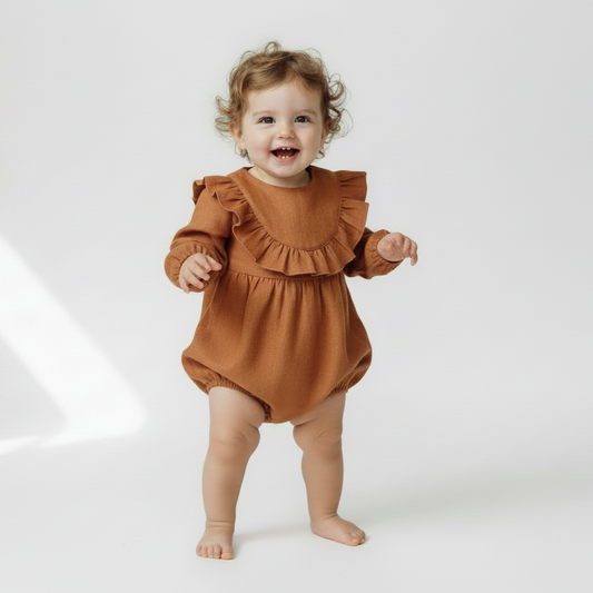 Child wearing a brown ruffled romper on a white background