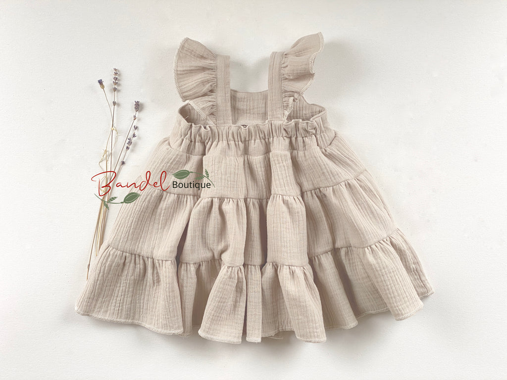 Beige ruffled dress on a white background with 'Raindel Boutique' branding.