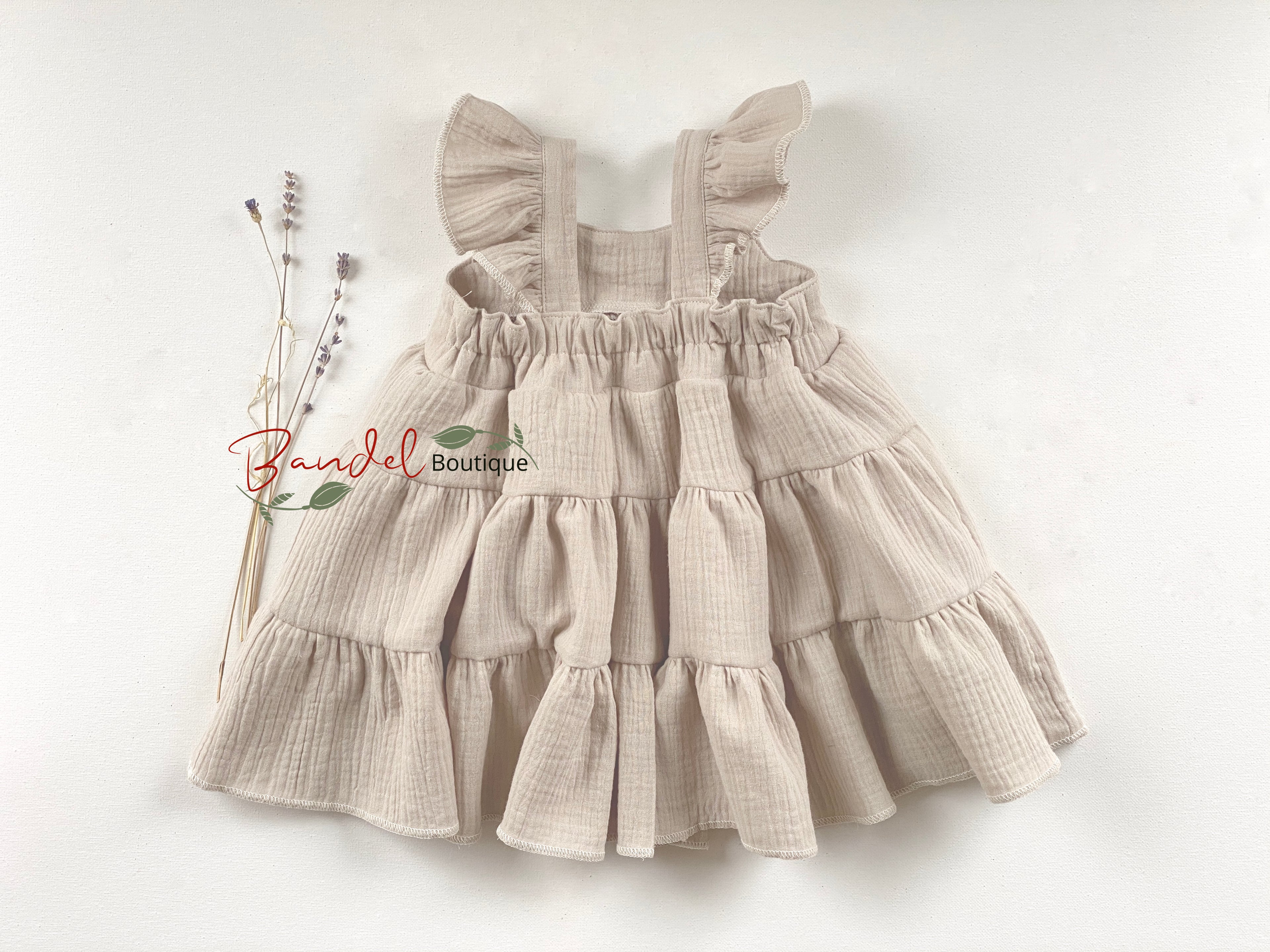 Beige ruffled dress on a white background with 'Raindel Boutique' branding.