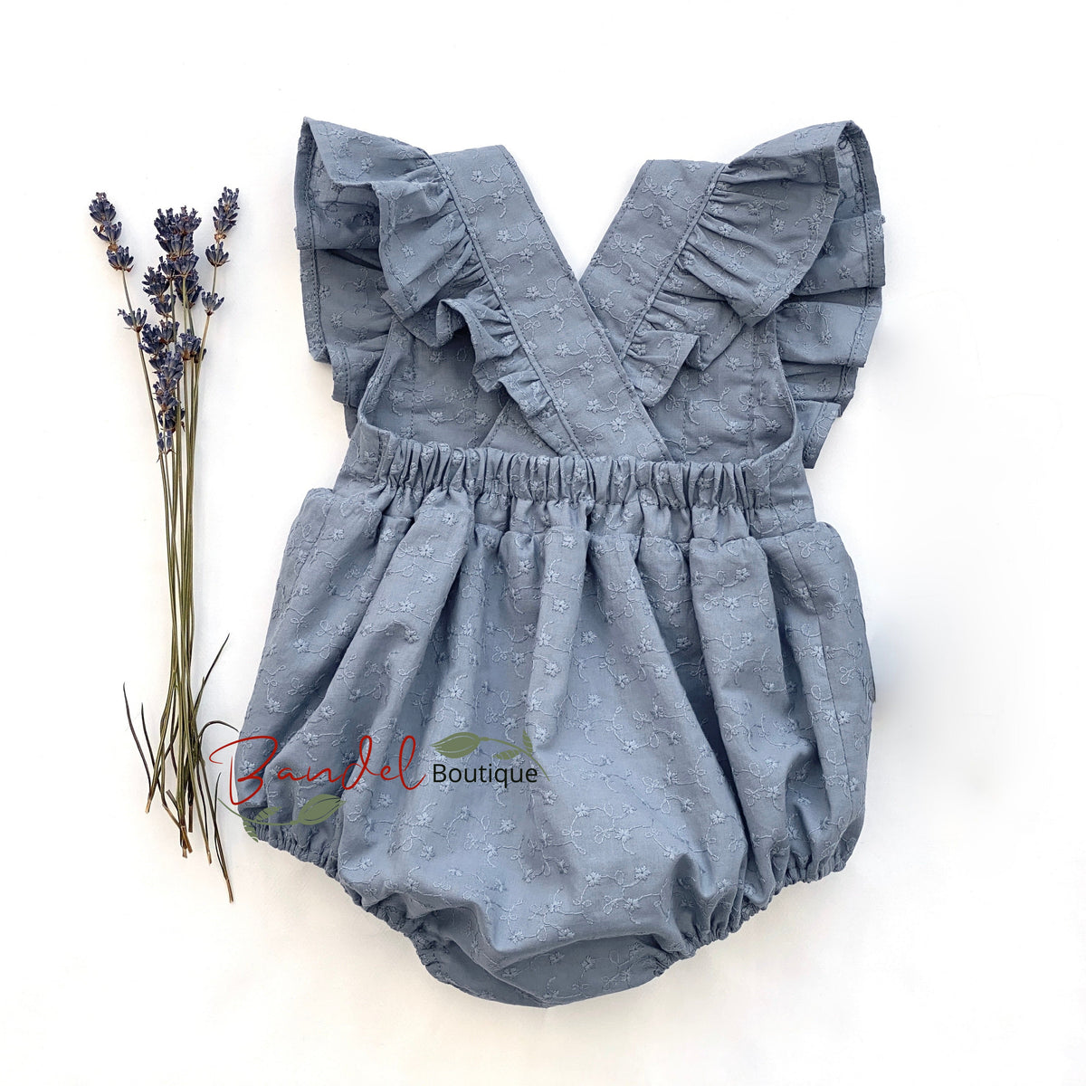 Blue denim romper with ruffled straps on a white background