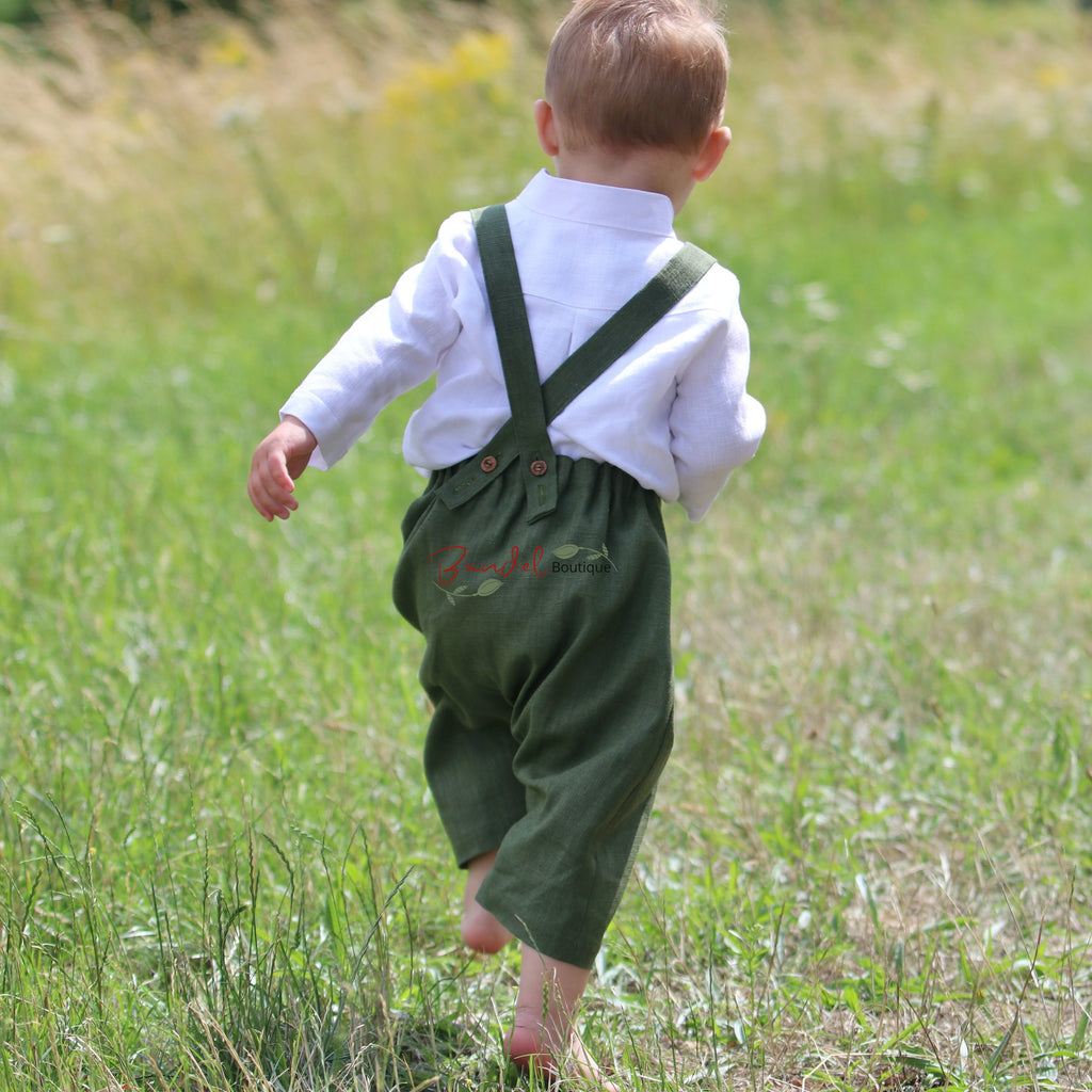 Child wearing green overalls and a white shirt walking in a grassy field