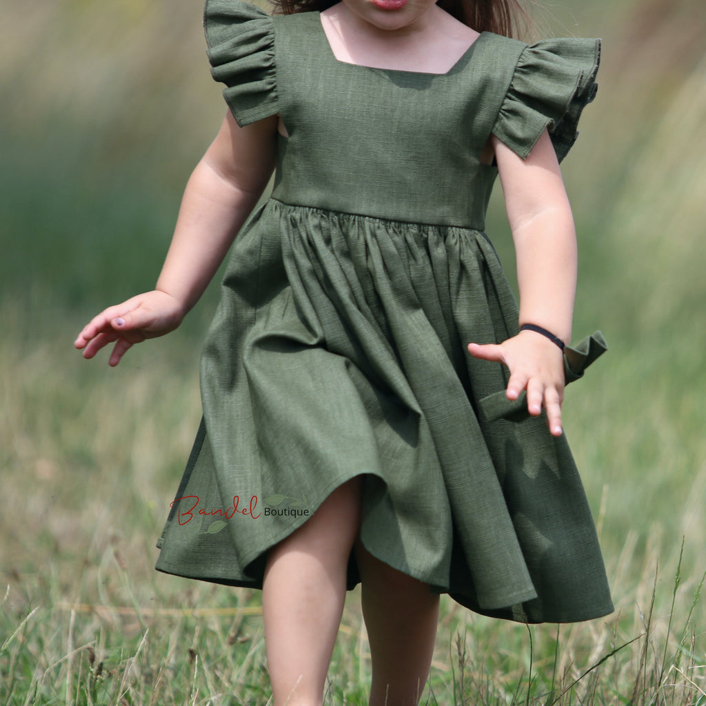 Child wearing a green dress in a grassy field