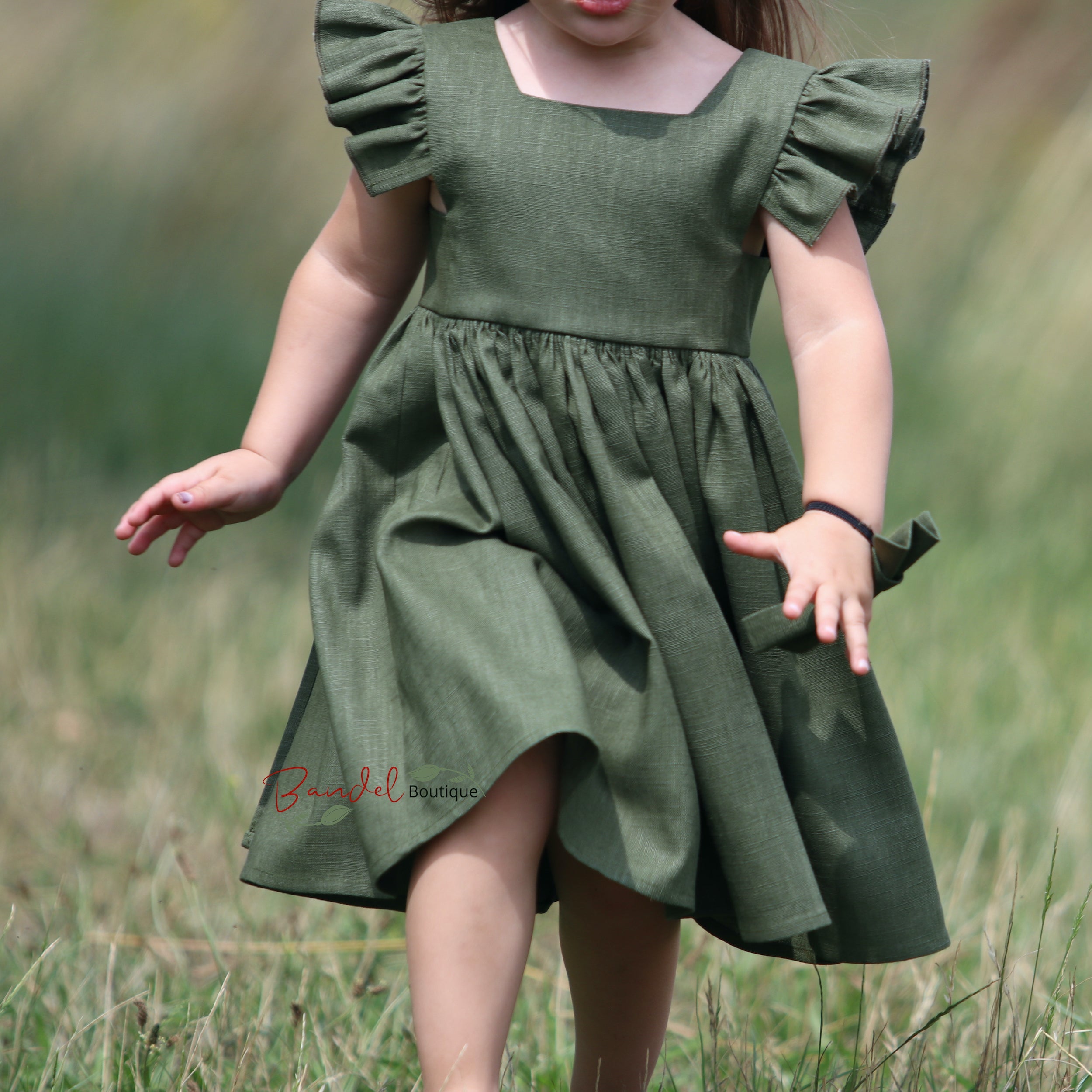 Child wearing a green dress in a grassy field