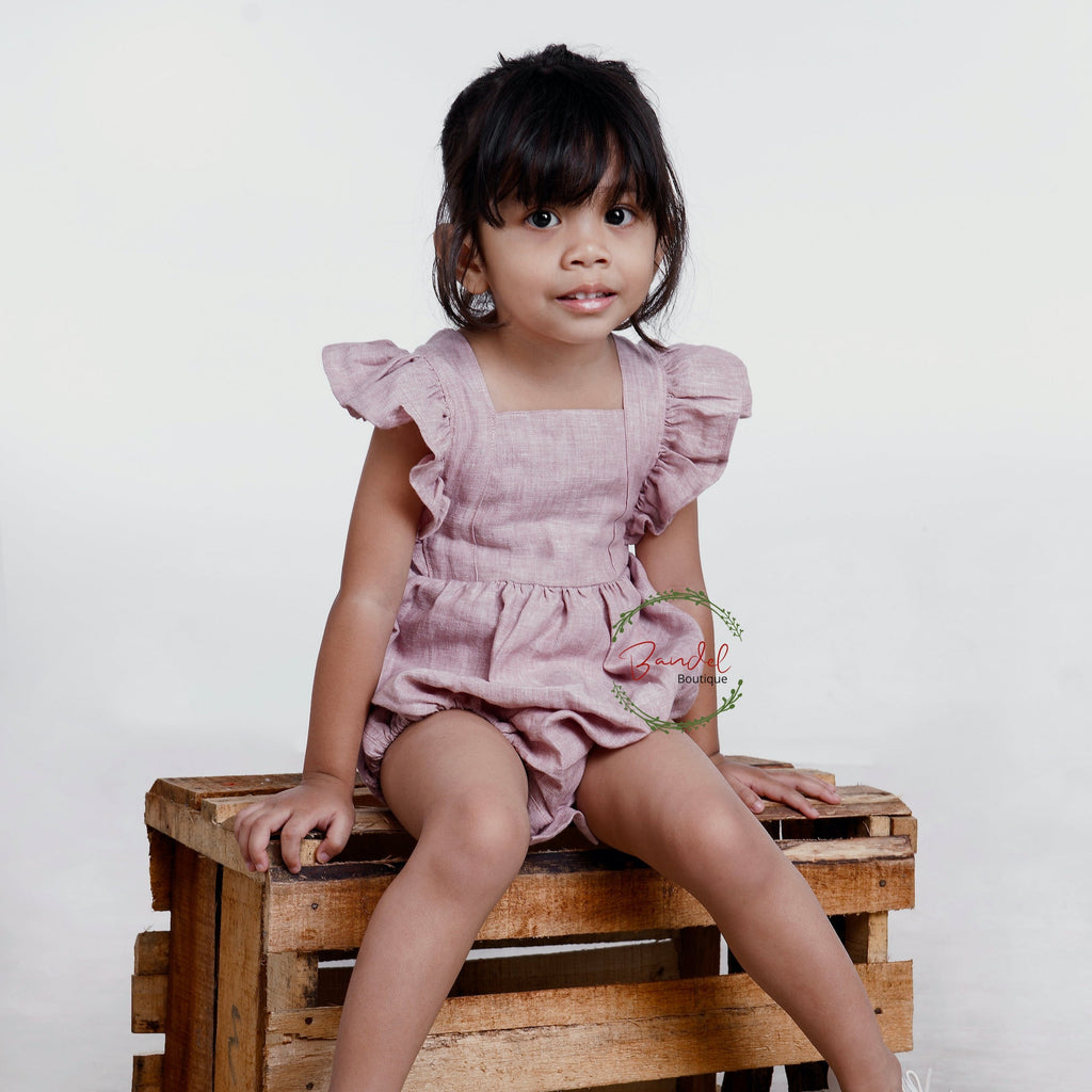 Child sitting on a wooden bench in a garden with flowers and greenery.