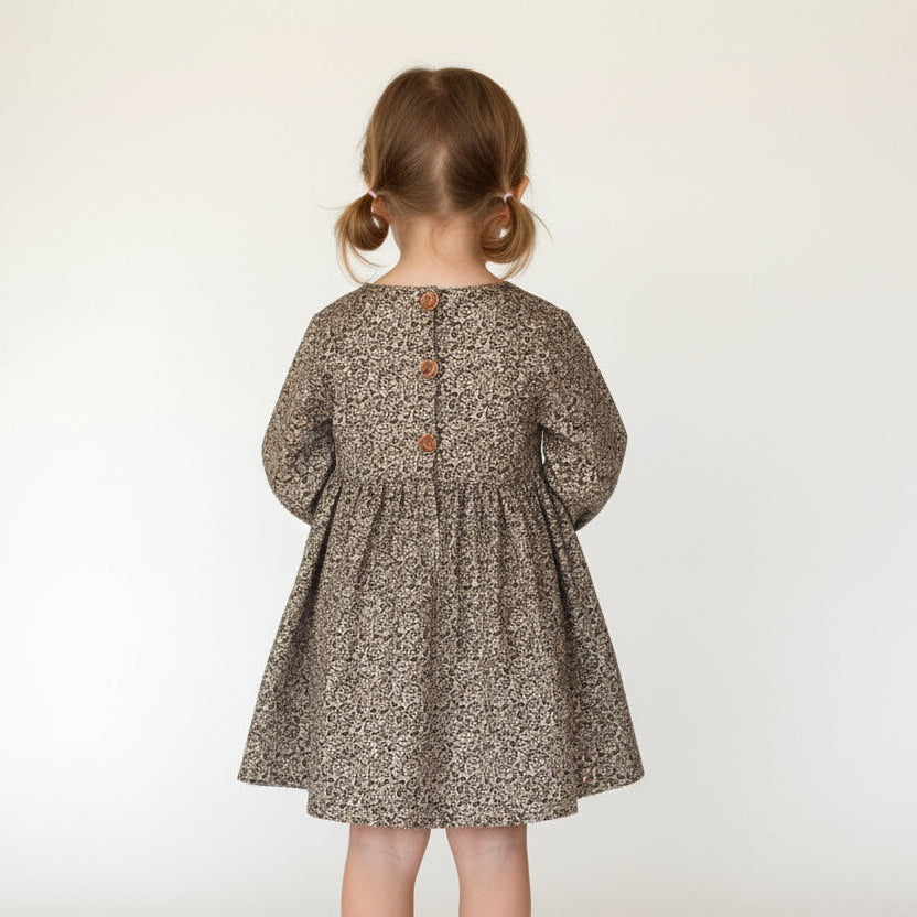 Child wearing a patterned dress on a plain background