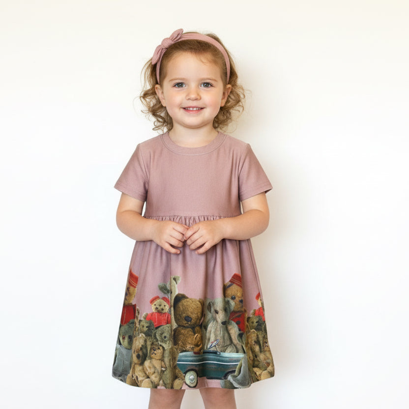 Young girl wearing a pink dress with animal print on a white background